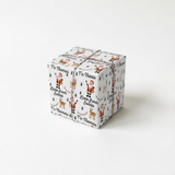A gift box wrapped in a Christmas-themed paper with Santa Claus and reindeer patterns.