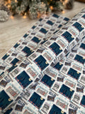 a roll of wrapping paper with a repeating pattern of Christmas-themed images, including buildings, snowflakes, and Christmas trees.
