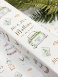a close-up view of a decorative wedding gift box with a repeating pattern of wedding-related items such as rings, flowers, and a cake.