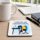 a desk with a coffee mug, a keyboard, a notebook, and a coaster with an illustration of a person sleeping at a desk.