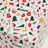 The image is a close-up of a Christmas-themed gift box with various holiday-related icons and text.