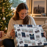 A woman is sitting on the floor, holding a large gift box with a Christmas-themed design.
