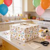 A birthday gift wrapped in a patterned paper with a hedgehog design, placed on a kitchen counter surrounded by colorful balloons and party decorations.