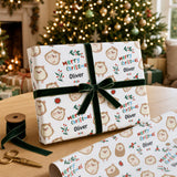 A gift wrapped in a white paper with a pattern of cartoon hedgehog characters, along with a green ribbon bow. The gift is placed on a table, with a pair of scissors and a spool of ribbon visible nearby. In the background, there is a Christmas tree with twinkling lights.