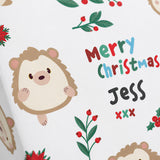 a close-up of a white background with various Christmas-themed illustrations, including a hedgehog, berries, leaves, and a personalized message.