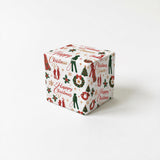 A white gift box with a festive Christmas-themed wrapping paper featuring various holiday symbols and text.