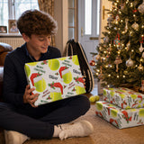 A young boy sits on the floor, holding a wrapped gift box with a tennis theme, smiling as he looks at it.