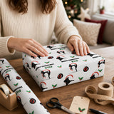A person is wrapping a gift box with a patterned wrapping paper featuring a karate-themed design.