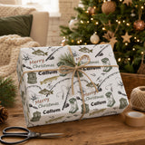 A gift wrapped in a patterned wrapping paper with fishing-related illustrations, sitting on a wooden surface next to a Christmas tree and other holiday decorations.