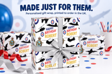a personalized gift wrap for a birthday, with the name "Robert" printed on it. The gift wrap is decorated with a pattern of military aircraft and has a gray ribbon tied around it. The background includes confetti and balloons, suggesting a festive occasion.