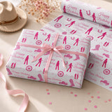 a gift box wrapped in pink paper with a bow, along with a hat and some pink confetti on a table.