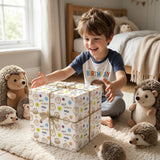 A young boy is sitting on the floor surrounded by stuffed hedgehogs, opening a gift box with a big smile on his face.