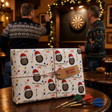 a festive gift wrapped in a pattern of dartboards and Christmas-themed designs, placed on a table with a dartboard and several darts nearby.
