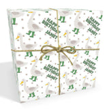 The image is a gift box wrapped in a white paper with a pattern of green ducks and white polka dots. The gift box is tied with a brown string, and the word "Happy Birthday" is written on it.