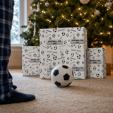 A Christmas tree with lights and ornaments, surrounded by wrapped gifts with soccer ball patterns. A soccer ball is placed on the floor in front of the gifts.