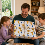 A man is holding a large gift box with a young girl and boy sitting next to him, all smiling and looking at the gift.