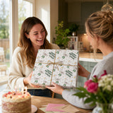 Two women are sharing a joyful moment, with one woman holding a gift box with a birthday design and the other woman smiling and looking at the gift.