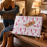 a gift wrapped in pink and white paper with a "Happy Birthday Sophie" message, placed on a wooden surface next to a pair of brown boots and a hat.
