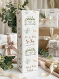 A tall, white gift box with a decorative design featuring a car, flowers, and other wedding-related elements. The text on the gift box reads "Mr & Mrs Selby" and "Sep 26th 2026".