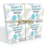 The image is a gift box with a birthday theme, featuring a happy first birthday for Noah. It is tied with a string and has a rainbow and clouds design.