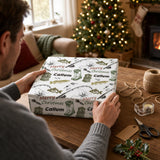 A person is wrapping a gift box with a Christmas-themed wrapping paper featuring illustrations of fishing and a Christmas tree.