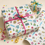 a gift box with a pink ribbon and a bow, decorated with various colorful illustrations and text, including the word "Sophie" and "90s" elements.