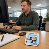 A man is sitting at a desk in an office, working on a computer. There is a sign on the desk that says "I Love My Job" and says " Said Dave never..."