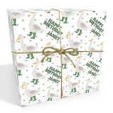 The image is a gift box wrapped in a white paper with a pattern of green ducks and white polka dots. The gift box is tied with a brown string, and the word "Happy Birthday" is written on it.
