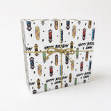 A gift box wrapped in a white paper with a pattern of colorful skateboards and stars.