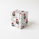 A white gift box with a pattern of Christmas-themed dartboards and Santa hats on it.
