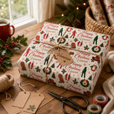 A festive Christmas gift wrapped in a patterned paper with the name 'Vanessa' printed on it, sitting on a wooden surface next to holiday decorations and a pair of scissors.