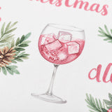 A close-up of a wine glass filled with a pink liquid, garnished with ice cubes, and surrounded by green leaves and pine cones.