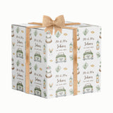 A gift box with a repeating pattern of wedding-related items, including a bride and groom, wedding rings, a cake, and a toaster. The text on the gift box reads "Mr & Mrs Johns" and "Est. 12.05.2023".