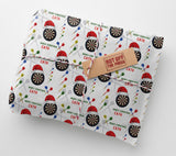 a gift wrapped in a paper with a repeating pattern of dartboards and Santa hats.